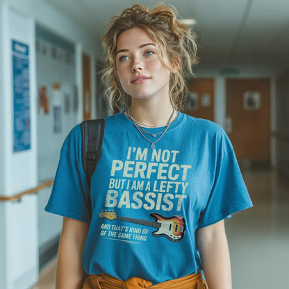 Unisex blue t-shirt featuring the text "I'm not perfect but I am a lefty bassist" with a lefty bass guitar graphic.