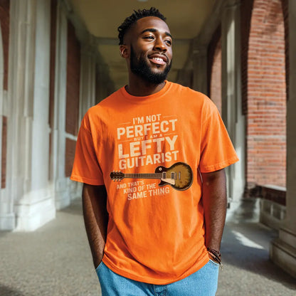 Orange unisex T-shirt featuring the text "I'm not perfect but I am a lefty guitarist" and a lefty guitar graphic.