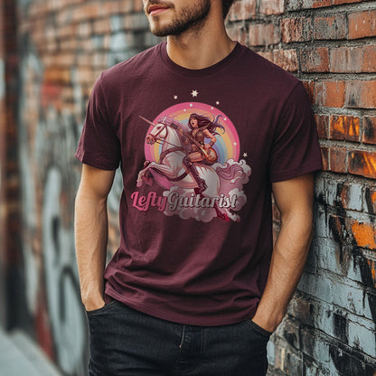 A man in a maroon unisex T-shirt featuring a unicorn and a warrior with the text "LeftyGuitarist" in a colorful design, leaning against a graffitied wall.