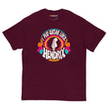 Maroon unisex t-shirt featuring a colorful graphic that reads "I play guitar like HENDRIX" with a guitar headstock illustration.