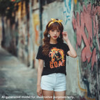 Black unisex T-shirt featuring "The G.O.A.T." graphic with a demon guitarist, worn by a Japanese woman walking along a sidewalk next to a graffiti-covered wall.